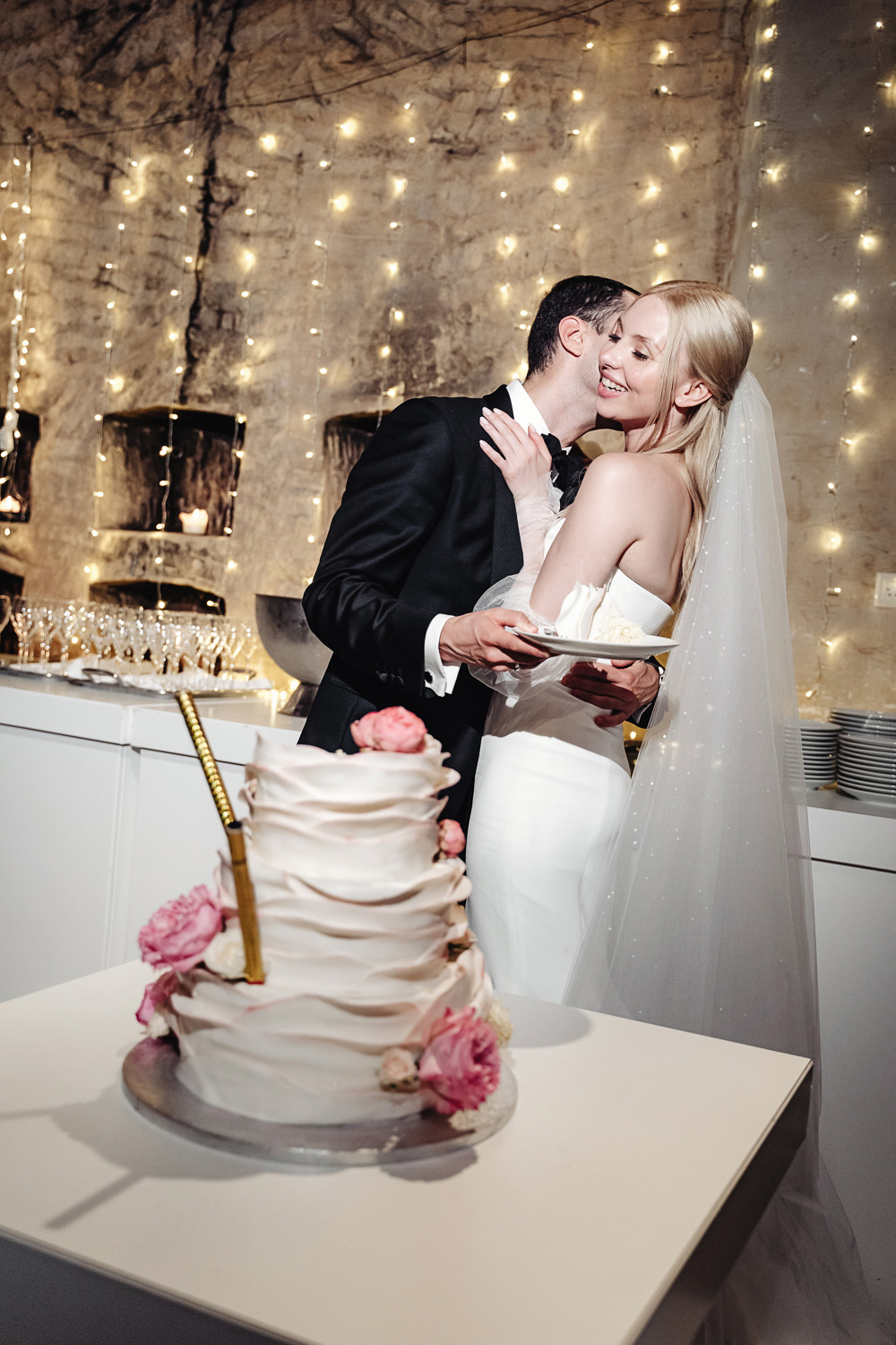 Bride and groom cut a wedding cake and after smiling and kissing