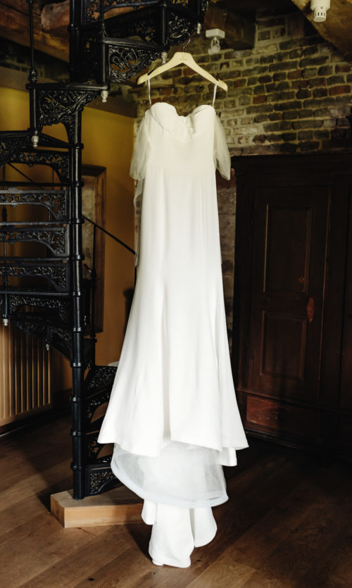 Wedding dress Vera Wang by Mercury hanging on a hanger near the stairs in nice interior