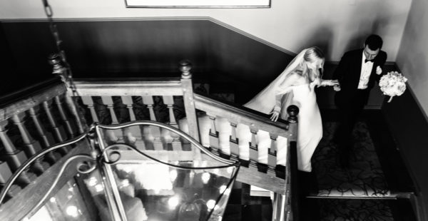 Trouwen ở Limburg. Bức ảnh đen trắng nơi cô dâu và chú rể đi xuống cầu thang sau khi làm lễ.